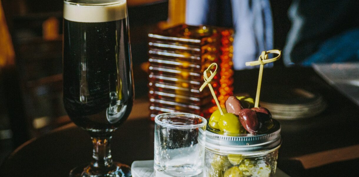 clear shot glass beside liquid filled footed glass